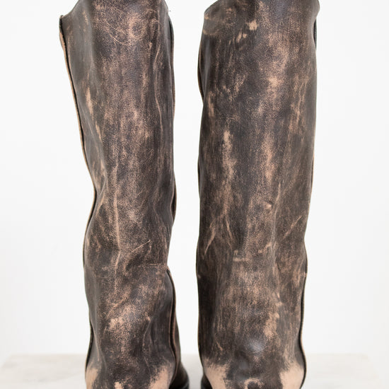 Pair of distressed brown leather boots on a white background