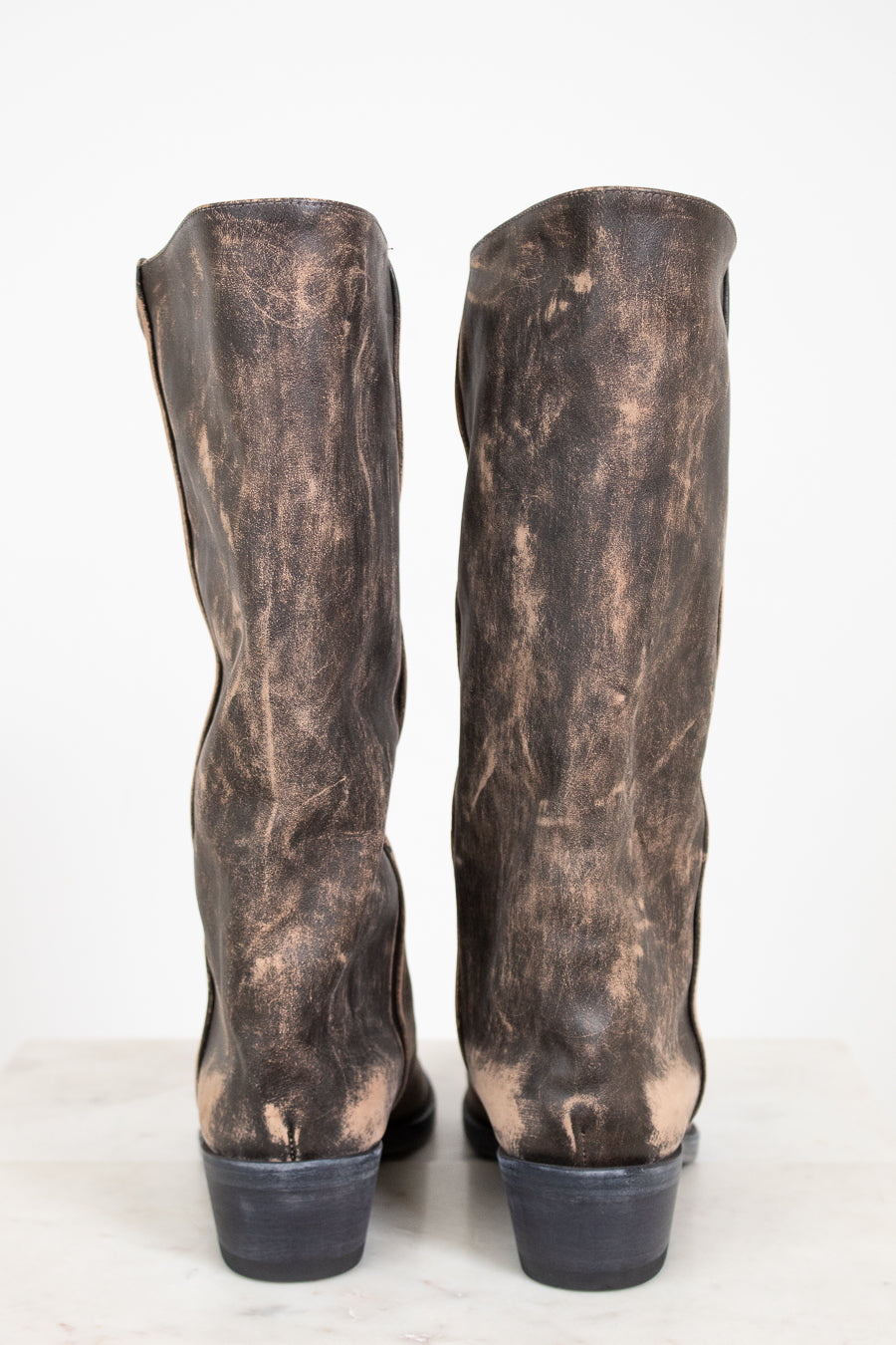 Pair of distressed brown leather boots on a white background