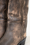 Close-up of brown leather boots with a distressed texture on a white background