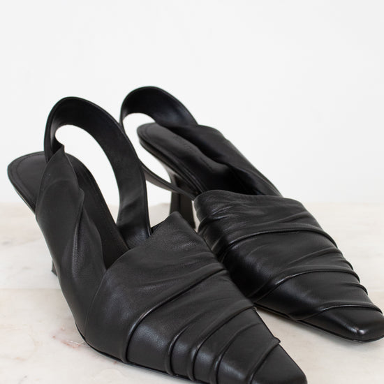 Pair of black leather slingback shoes on a light background