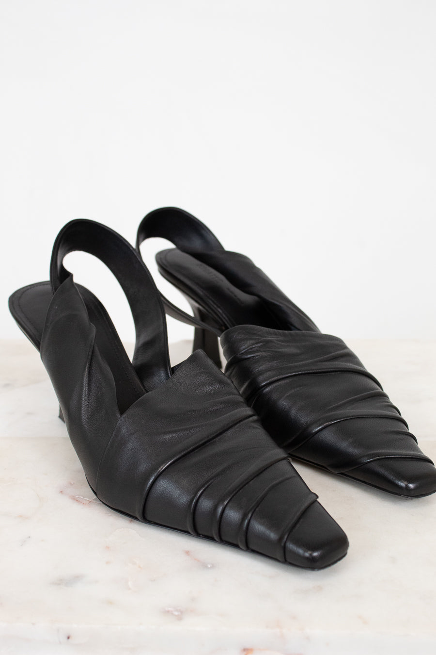 Pair of black leather slingback shoes on a light background