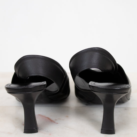 Black high-heeled sandals on a marble surface