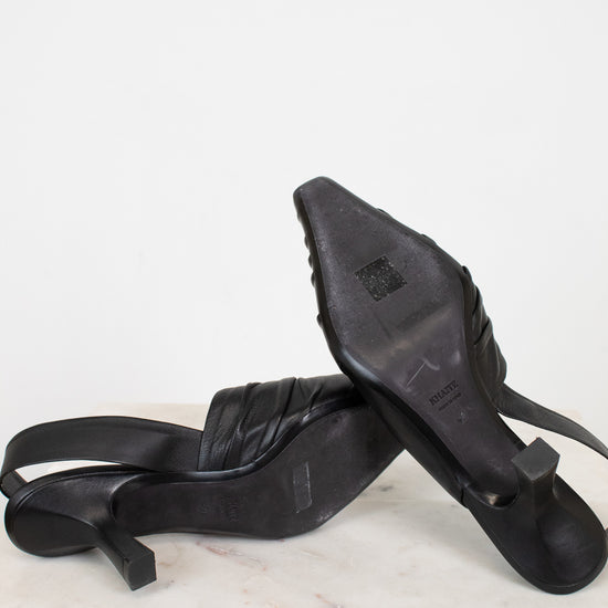 Black high-heeled shoes on a white marble surface