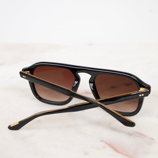 Black sunglasses with brown lenses on a white marble surface