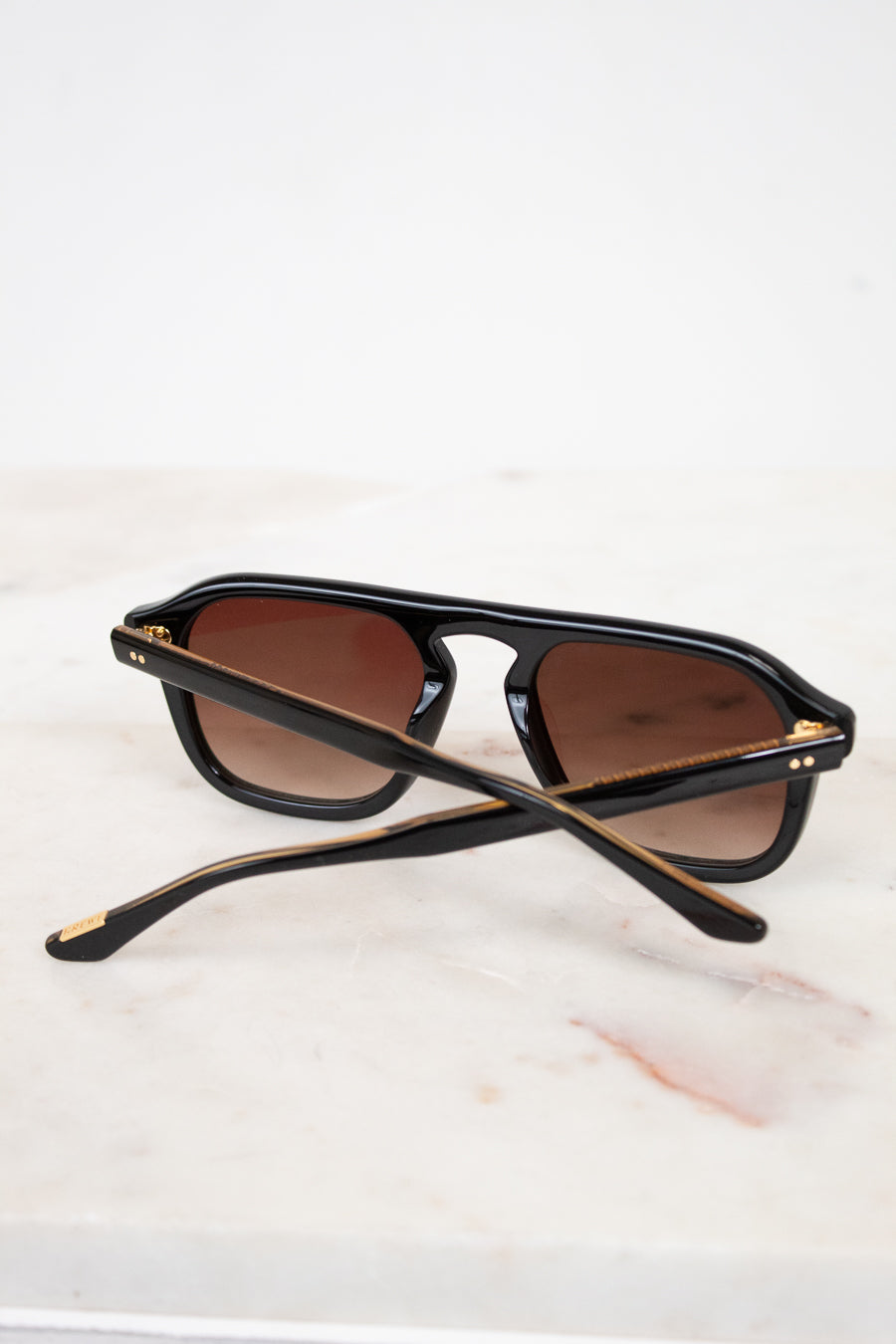 Black sunglasses with brown lenses on a white marble surface