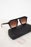 Black sunglasses with brown lenses on a black case against a white background