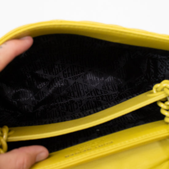 Close-up of a yellow bag with a hand holding it open, showing black interior.