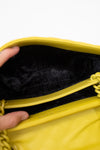 Close-up of a yellow bag with a hand holding it open, showing black interior.