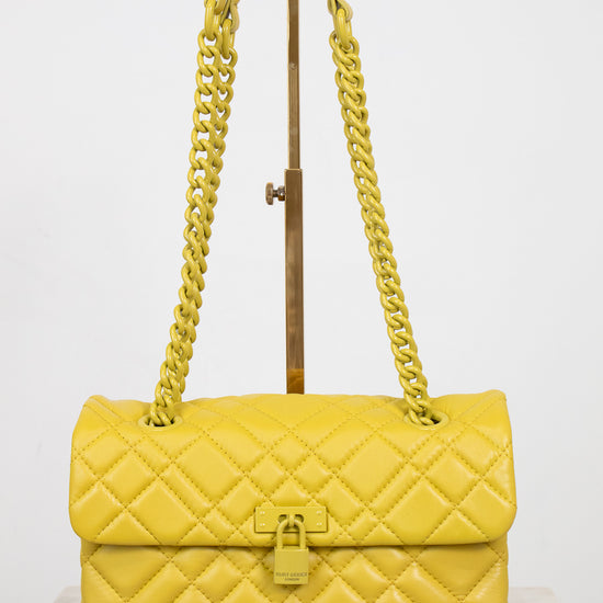 Yellow quilted handbag with chain strap on a white background