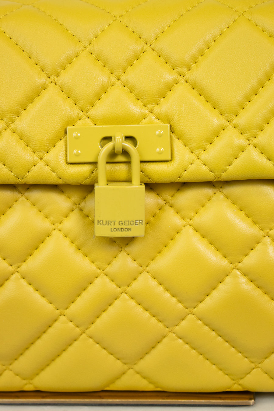Yellow quilted handbag with a visible Kurt Geiger brand logo on a light background