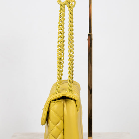 Yellow quilted handbag with yellow chain strap on a white background