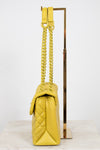 Yellow quilted handbag with yellow chain strap on a white background