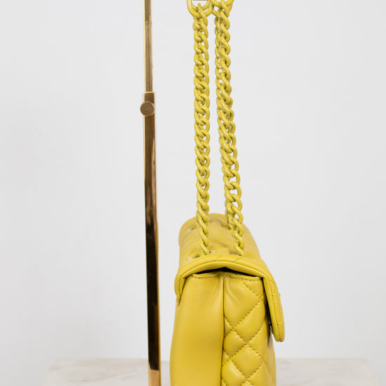 Yellow quilted handbag with a yellow chain on a white background