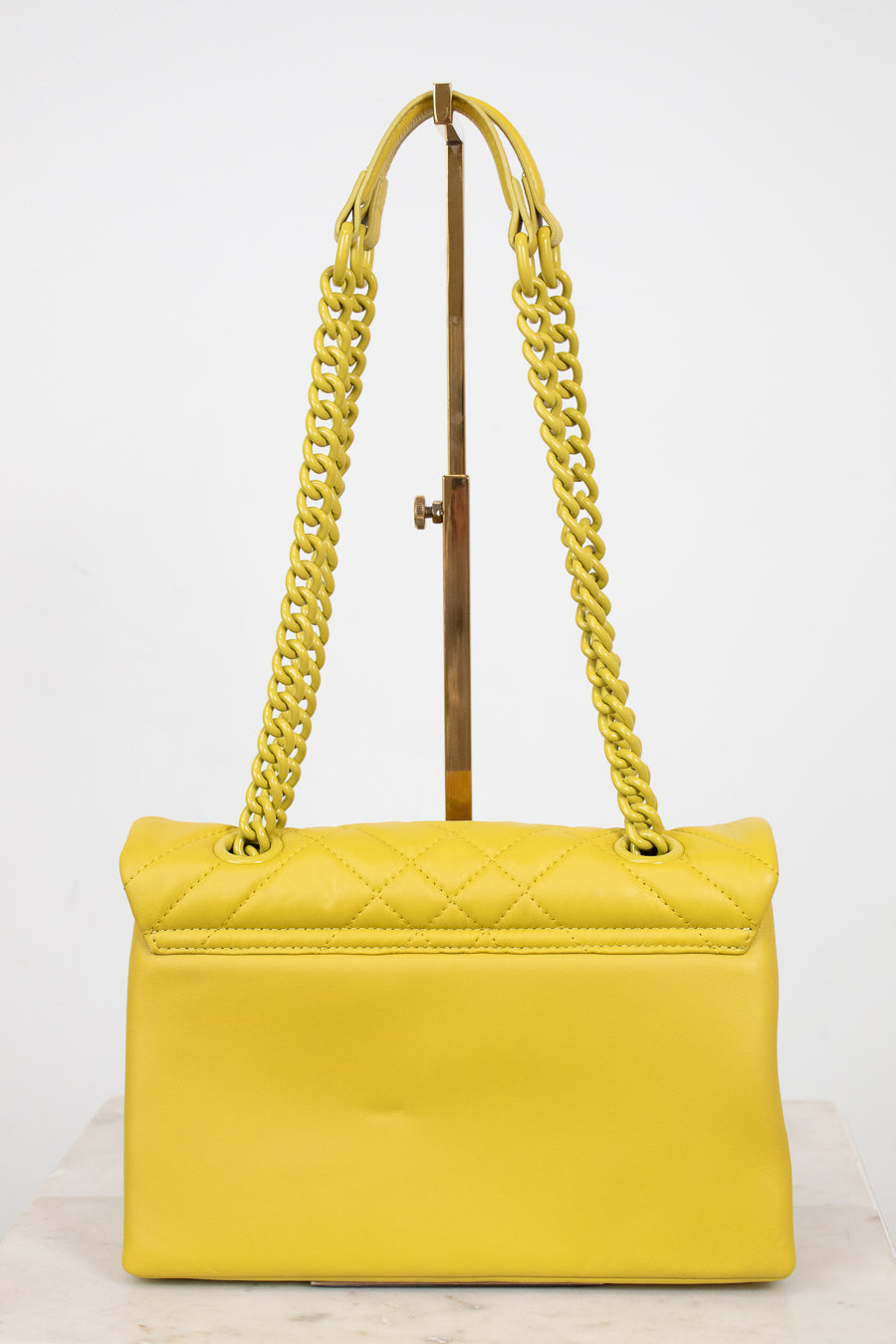 Yellow handbag with yellow chain straps on a white background
