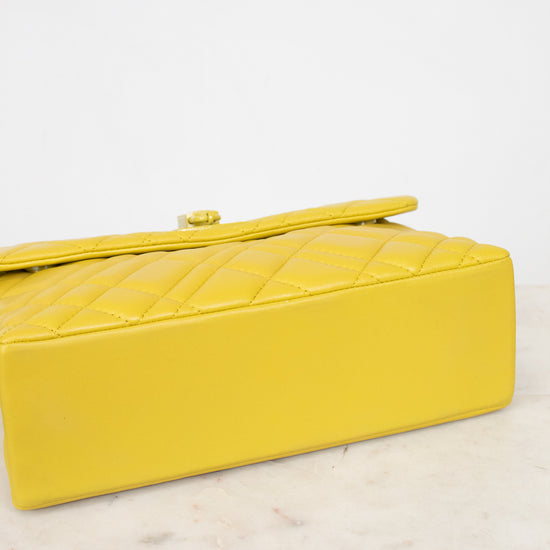 Yellow quilted handbag on a light marble surface with a white background