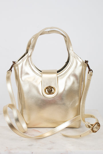 Gold handbag with shoulder strap on a light gray background