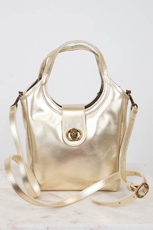 Gold handbag with shoulder strap on a light gray background