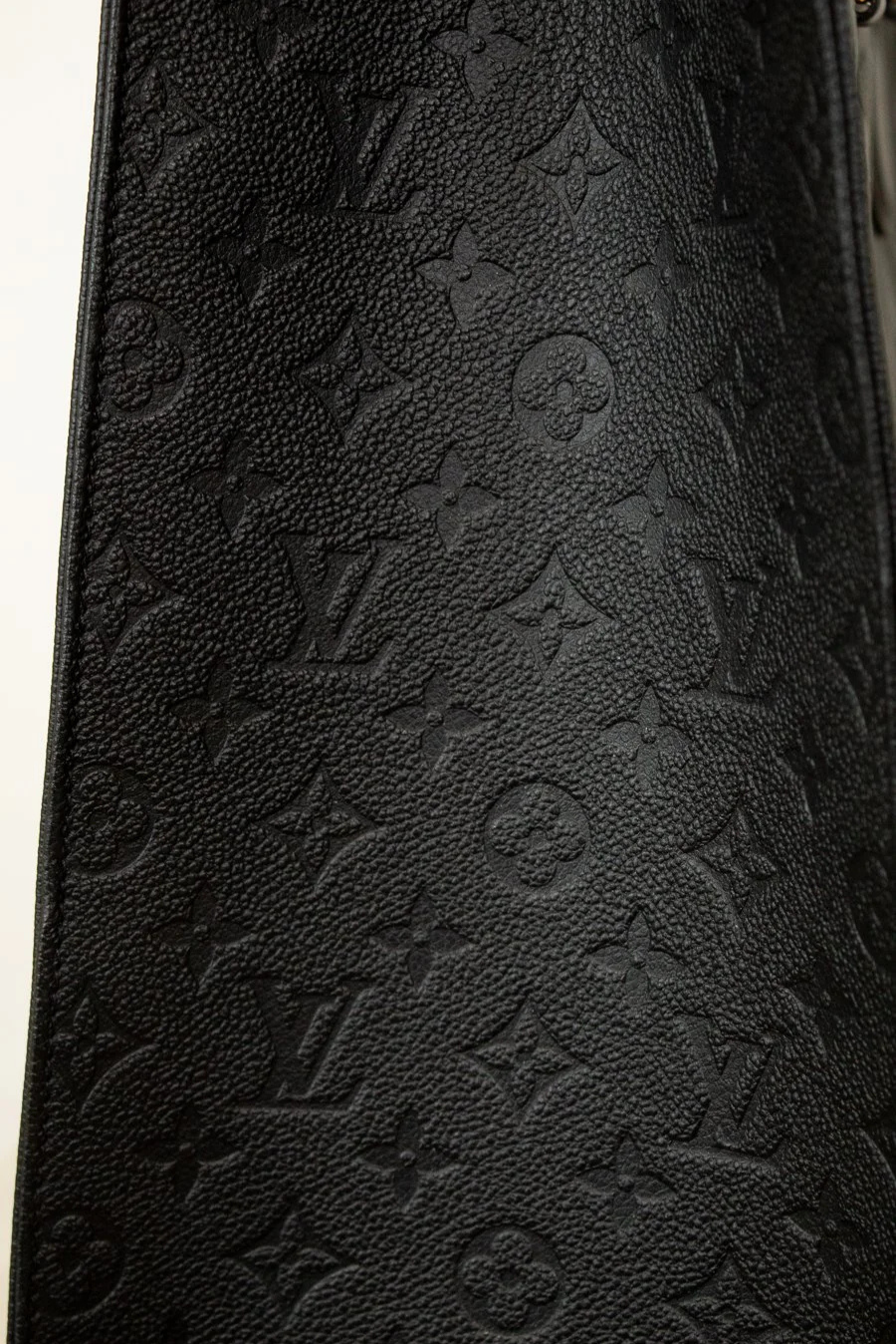 Close-up of a black leather wallet with embossed logo pattern