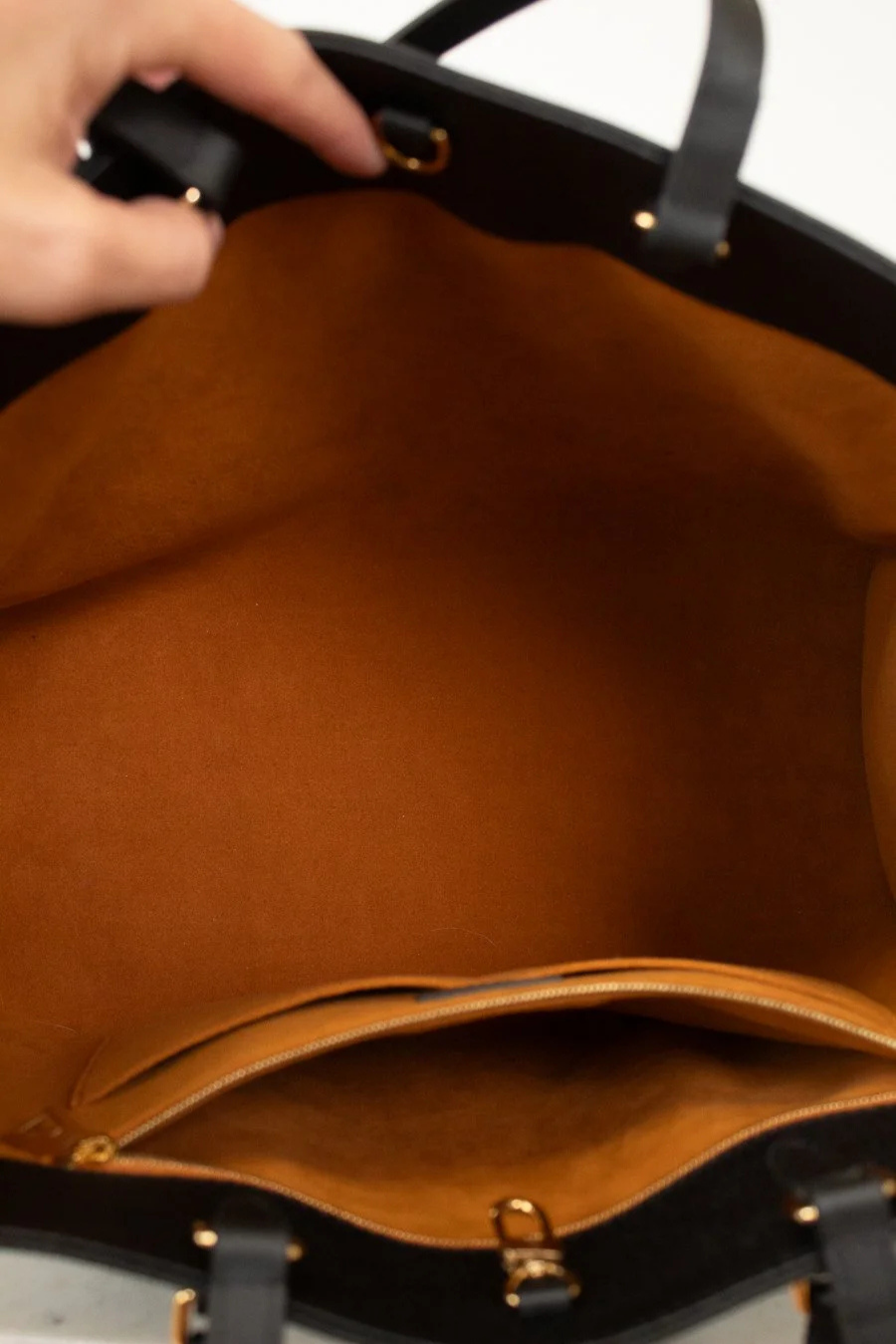 Close-up of interior brown suede with a hand holding it open.