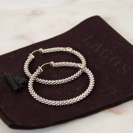 Silver hoops rested on brown dustbag on white background