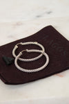 Silver hoops rested on brown dustbag on white background