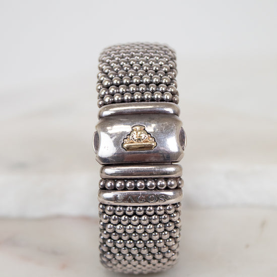 Silver beaded bracelet with a gold accent on a marble surface