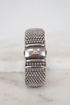 Silver beaded bracelet with a gold accent on a marble surface