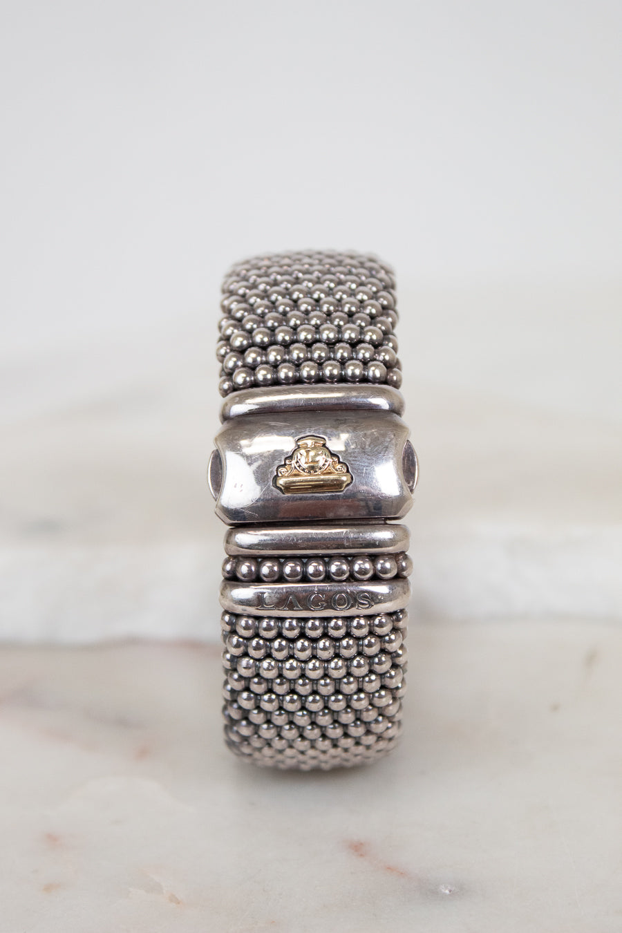 Silver beaded bracelet with a gold accent on a marble surface