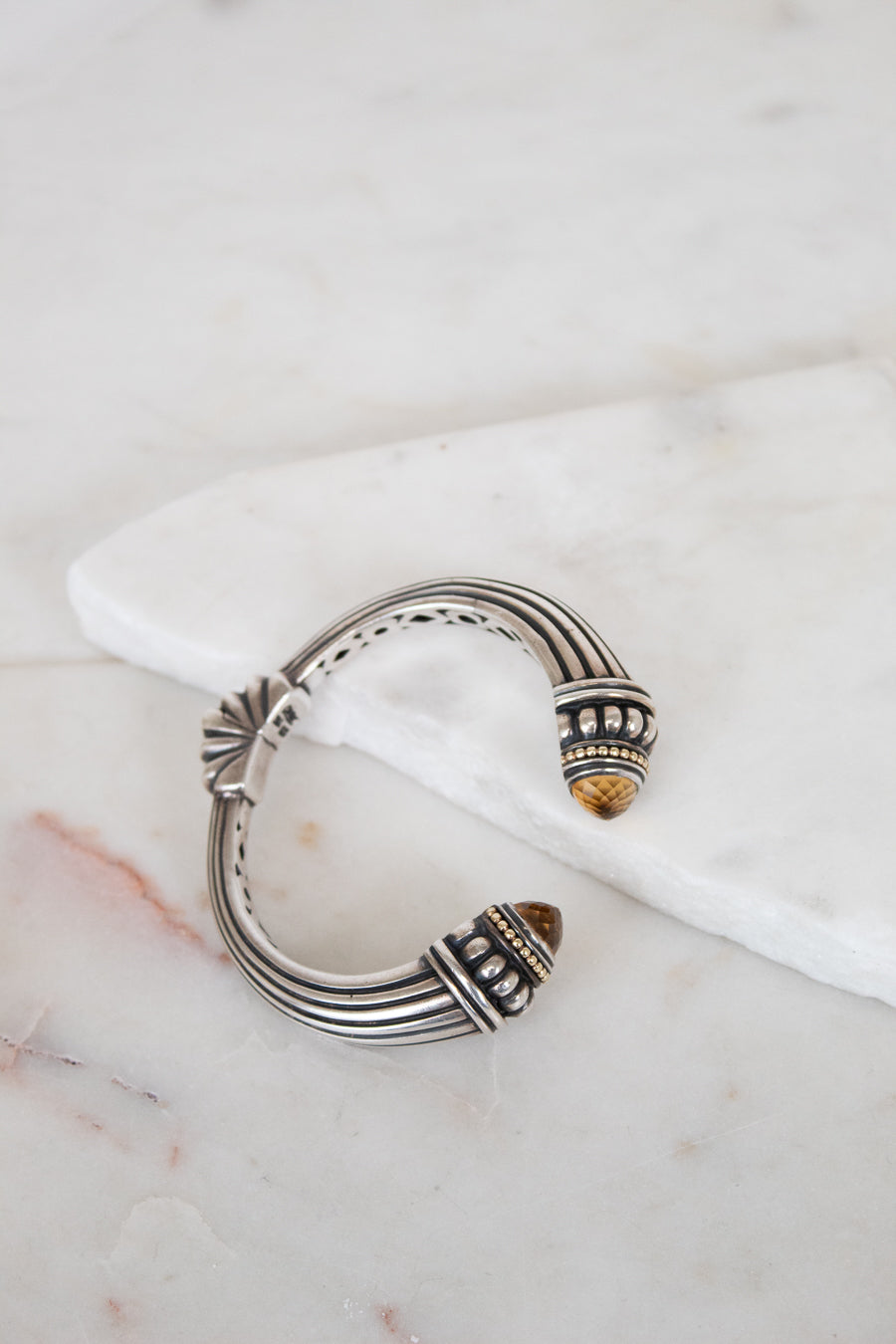 Silver bracelet with intricate design on a marble surface