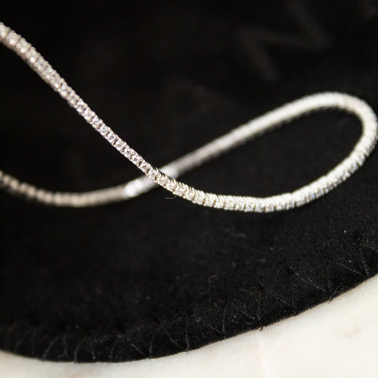 Silver and diamond bracelet on a black dust bag with a marble surface