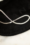 Silver and diamond bracelet on a black dust bag with a marble surface