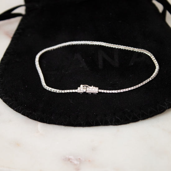Bracelet on a black drawstring bag with 'LANA' branding on a marble surface