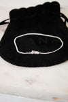 Bracelet on a black drawstring bag with 'LANA' branding on a marble surface