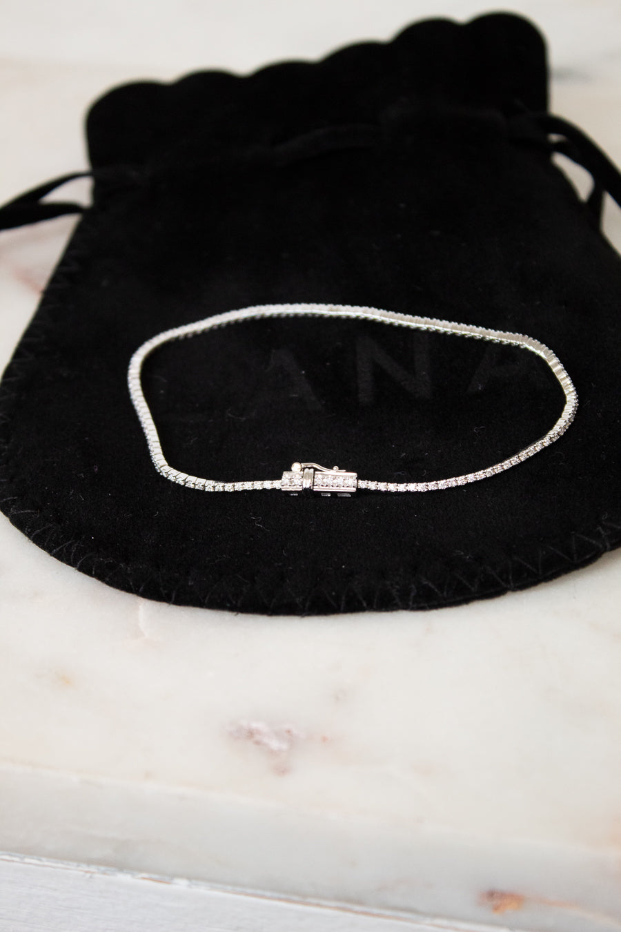Bracelet on a black drawstring bag with 'LANA' branding on a marble surface
