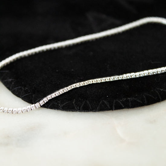 Silver and diamond bracelet on a black and white surface