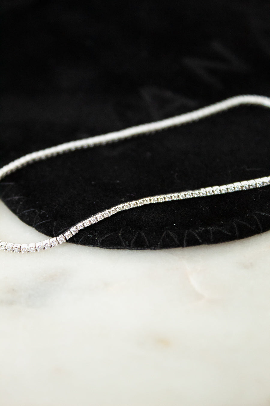 Silver and diamond bracelet on a black and white surface