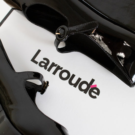 Close-up of a black and white product with 'Larroude' branding on a white background