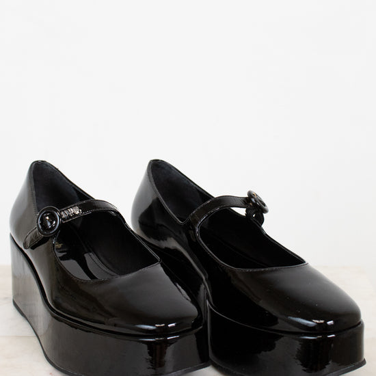 Black platform shoes with a strap on a white background