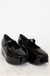 Black platform shoes with a strap on a white background