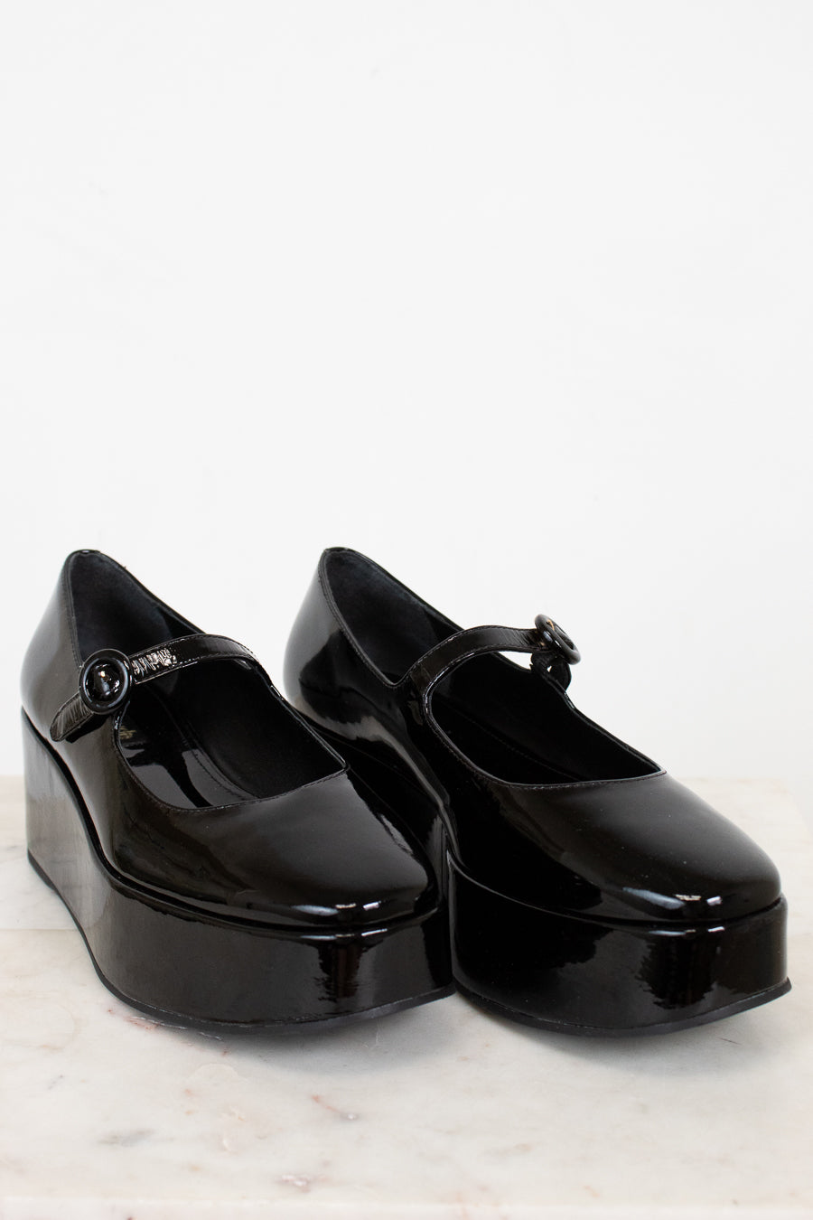 Black platform shoes with a strap on a white background
