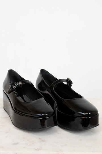 Black platform shoes with a strap on a white background