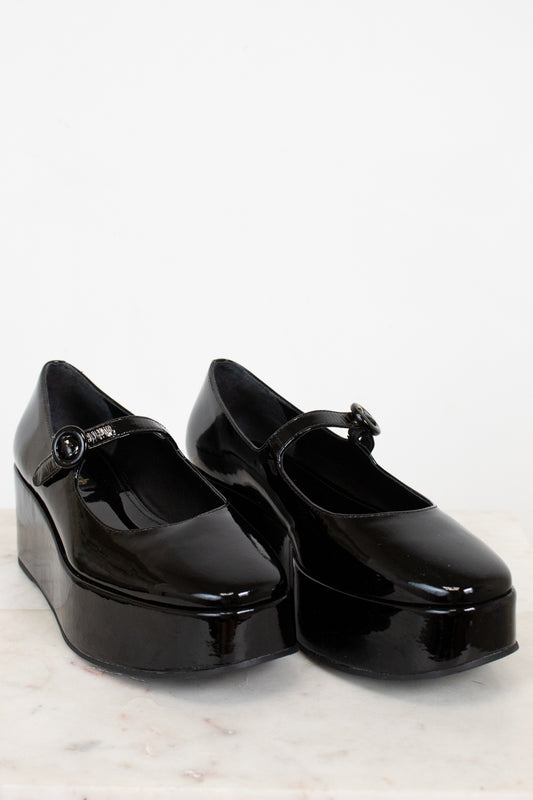 Black platform shoes with a strap on a white background