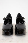 Pair of black patent leather shoes on a light background
