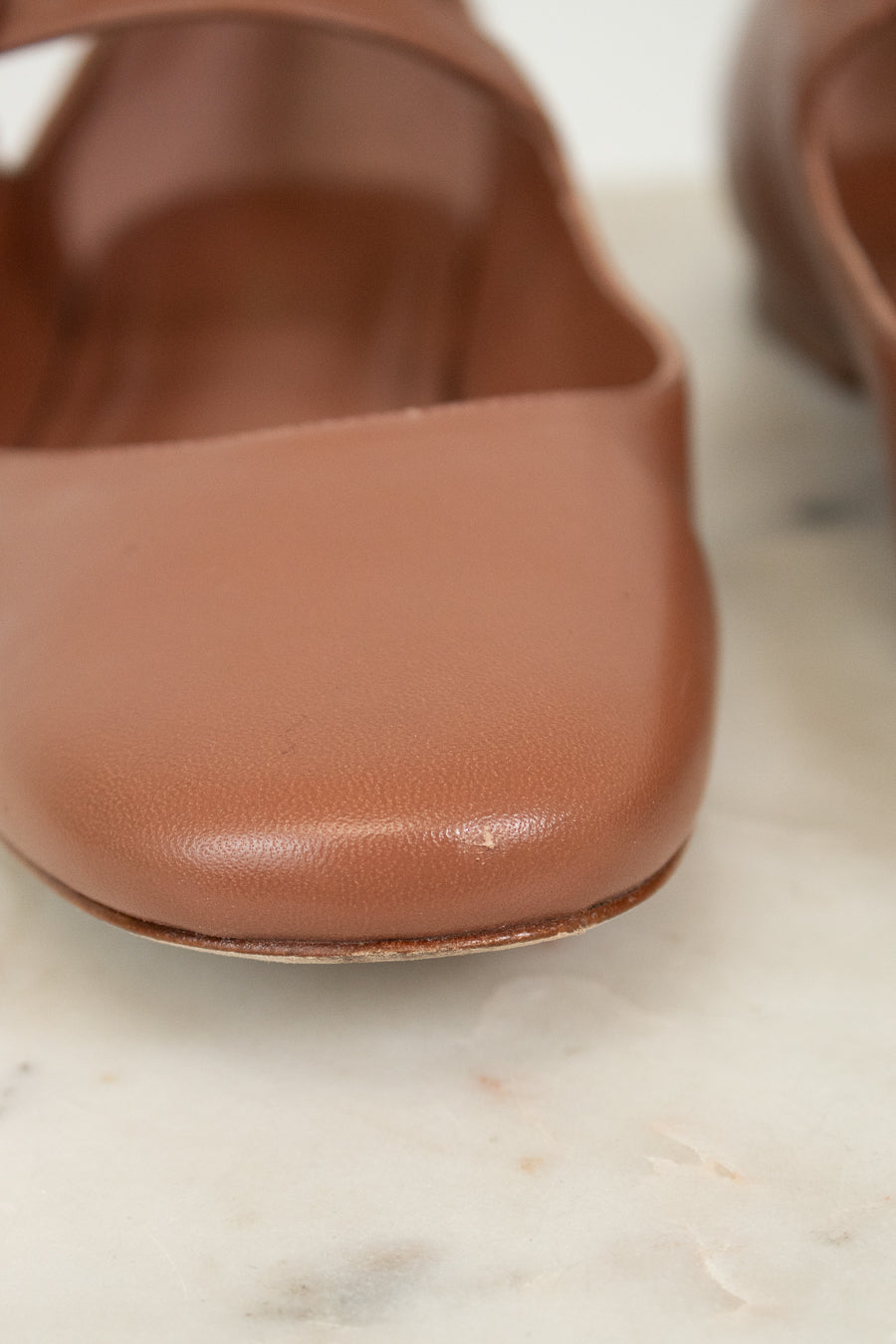 Close-up of a brown leather shoe on a light marble surface