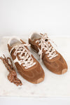 A pair of brown suede sneakers with cream and brown patterned laces, displayed on a white marble surface against a white background.