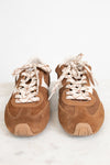 A pair of vintage-style brown suede sneakers with white side stripes and chunky cream rope laces, shown from the front on a light marble surface against a white background.