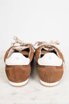 A pair of brown suede low-top sneakers shown from the back, featuring white heel tabs and cream-colored laces, set against a light gray background.