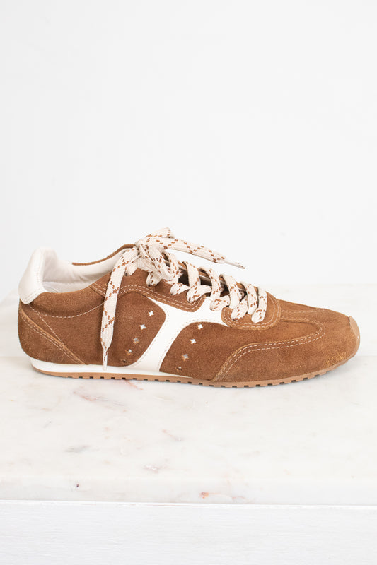 A single brown suede sneaker with cream-colored laces and side stripes, displayed on a white marble surface against a white background.