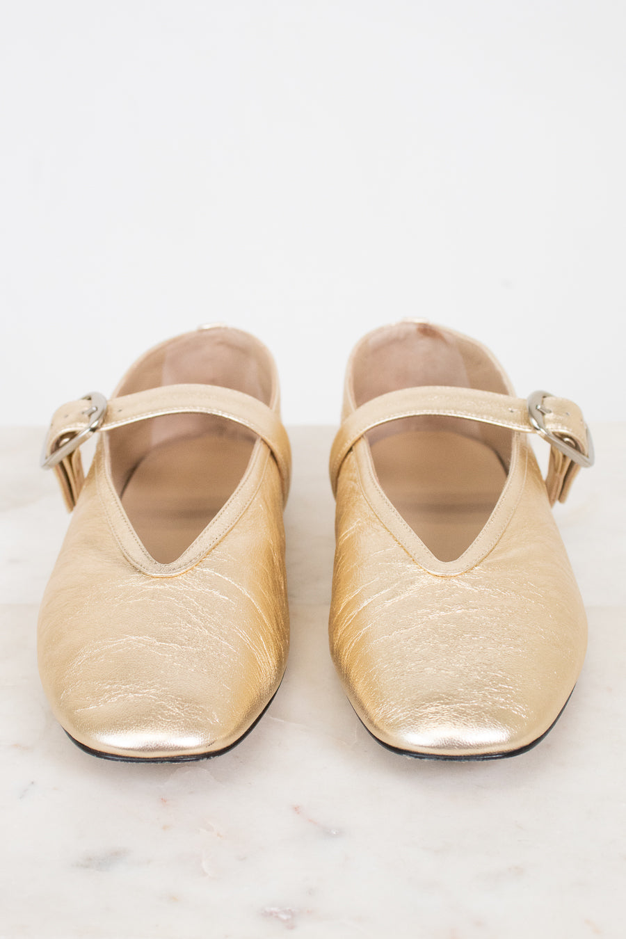 Pair of gold shoes with straps on a white background