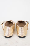 Pair of gold flat shoes on a light marble background